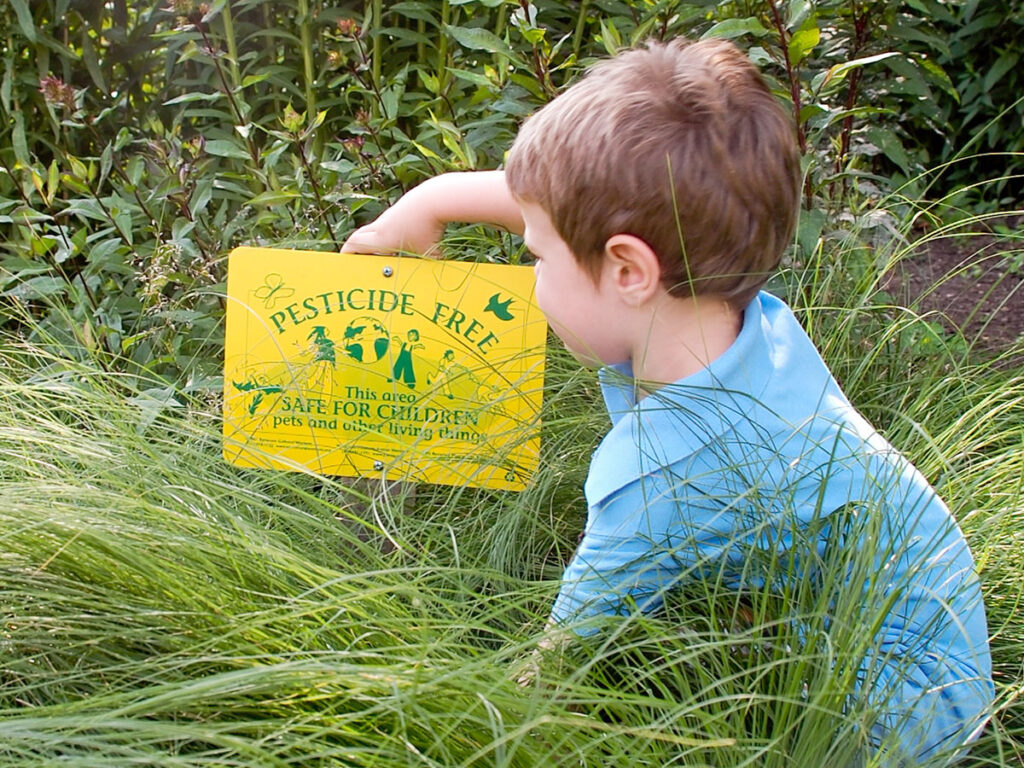 Child with pesticide sign